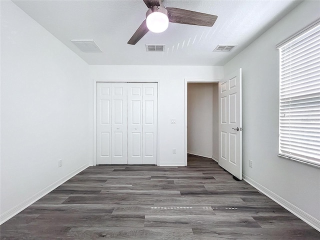 unfurnished bedroom featuring dark wood-type flooring, a closet, and ceiling fan