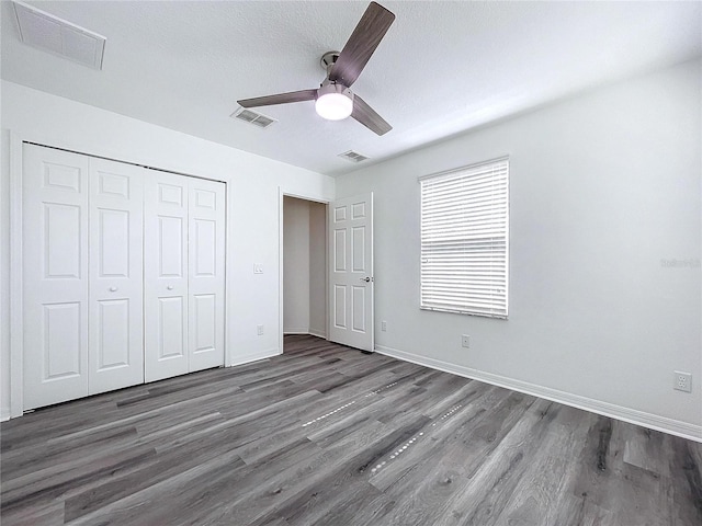 unfurnished bedroom featuring dark hardwood / wood-style flooring, a closet, a textured ceiling, and ceiling fan