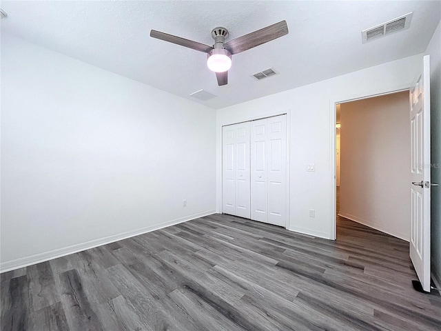 unfurnished bedroom with dark wood-type flooring, a textured ceiling, a closet, and ceiling fan