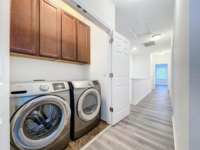 laundry room with cabinets, washer and dryer, and light wood-type flooring