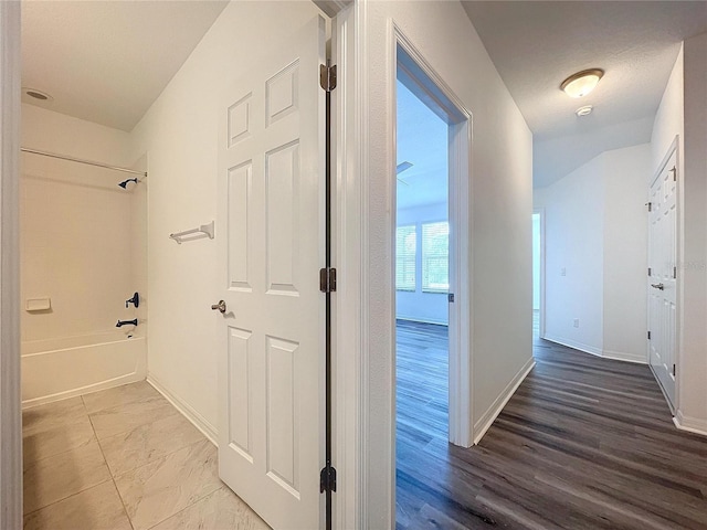 hall with a textured ceiling and wood-type flooring