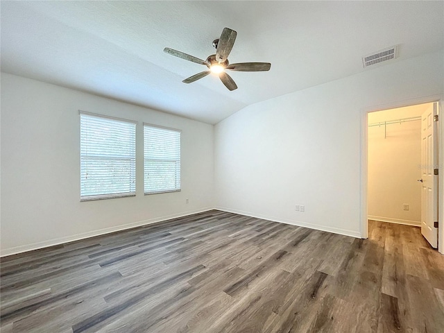 empty room featuring ceiling fan, vaulted ceiling, and dark hardwood / wood-style floors