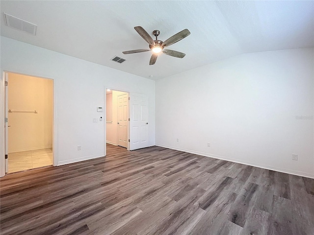 unfurnished bedroom with ensuite bath, dark wood-type flooring, vaulted ceiling, and ceiling fan