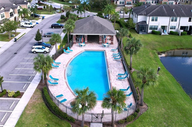 view of pool featuring a patio, a water view, and a lawn