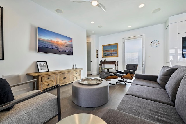 living room with ceiling fan and dark tile patterned floors