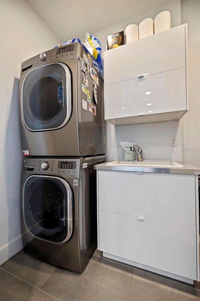 clothes washing area featuring cabinets, sink, and stacked washer and clothes dryer