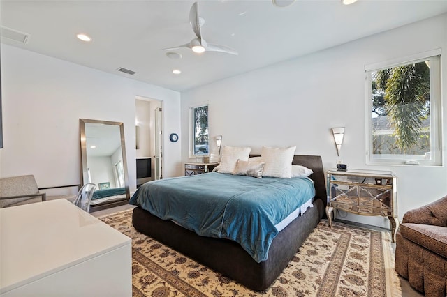 bedroom with hardwood / wood-style flooring, ceiling fan, and connected bathroom