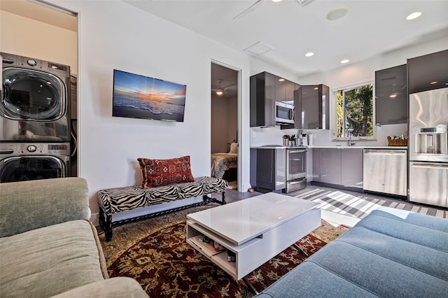 living room with stacked washer and clothes dryer and sink