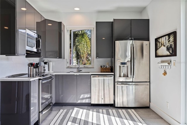 kitchen featuring stainless steel appliances, light tile patterned flooring, sink, gray cabinets, and decorative backsplash