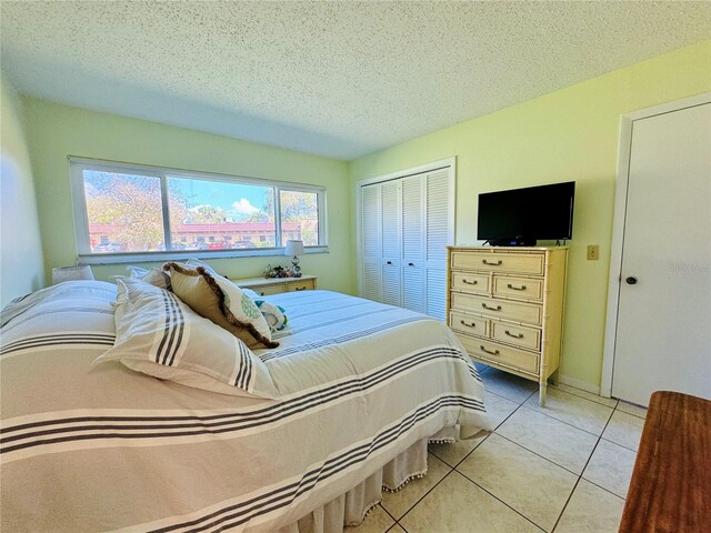 bedroom featuring a closet, a textured ceiling, and light tile patterned floors