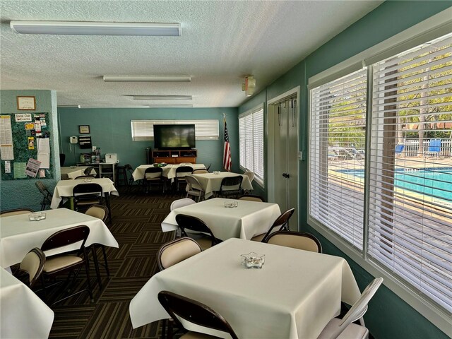 dining area with a textured ceiling and dark colored carpet