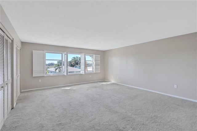 spare room with light carpet and a textured ceiling