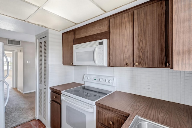 kitchen featuring tile patterned floors, a drop ceiling, white appliances, and tasteful backsplash