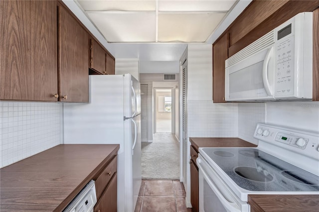 kitchen with light tile patterned flooring, backsplash, and white appliances