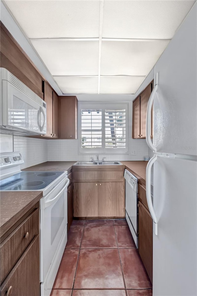 kitchen featuring dark tile patterned floors, sink, decorative backsplash, and white appliances