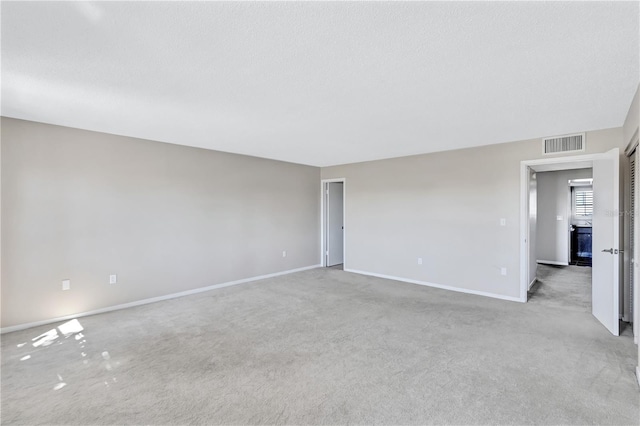 unfurnished room with a textured ceiling and light colored carpet