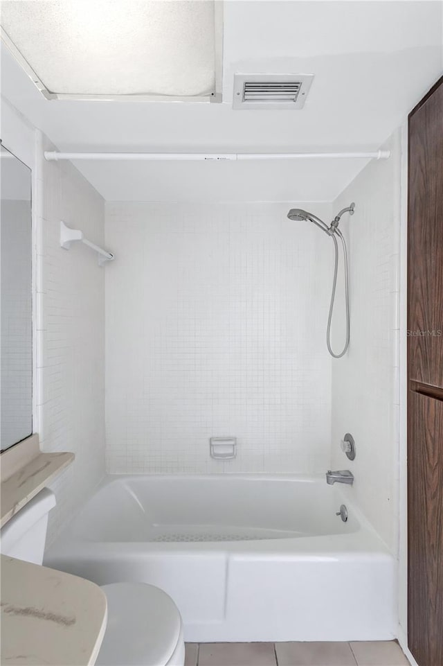 bathroom featuring toilet, tiled shower / bath combo, and tile patterned flooring