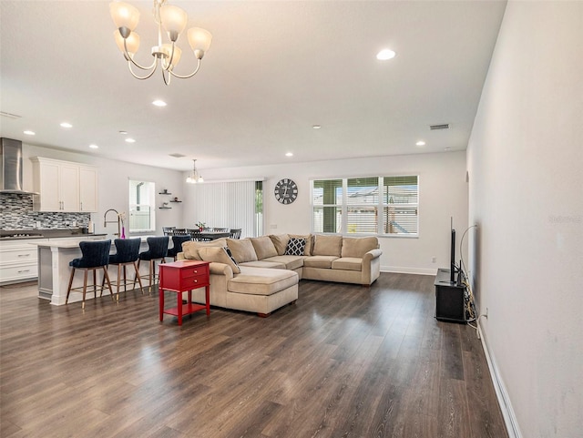 living room with a notable chandelier, sink, and dark hardwood / wood-style floors