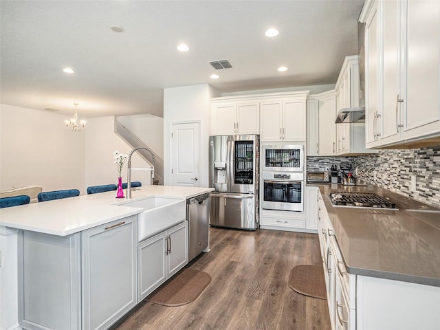 kitchen featuring appliances with stainless steel finishes, sink, an island with sink, white cabinets, and dark hardwood / wood-style floors