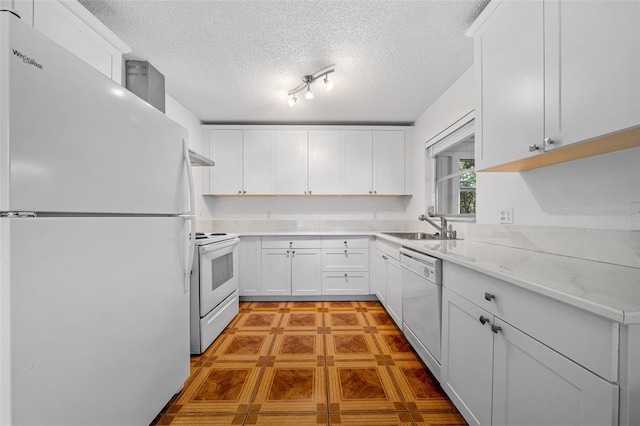 kitchen featuring a textured ceiling, sink, light stone countertops, white cabinetry, and white appliances