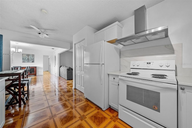 kitchen featuring white cabinetry, ceiling fan with notable chandelier, a textured ceiling, white appliances, and wall chimney range hood