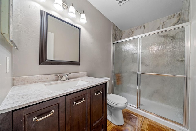 bathroom featuring vanity, toilet, and a shower with door