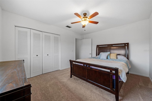 bedroom with light colored carpet, ceiling fan, and a closet