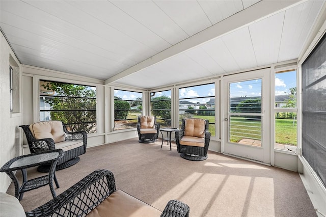 sunroom / solarium featuring beamed ceiling and a healthy amount of sunlight