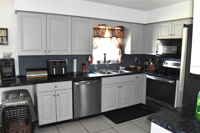 kitchen with appliances with stainless steel finishes, light tile patterned flooring, sink, and gray cabinets