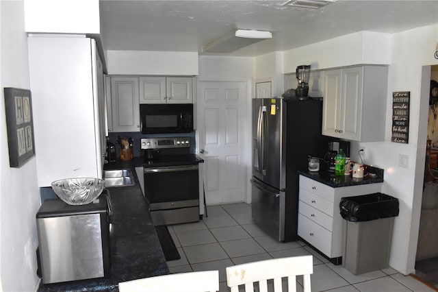 kitchen with stainless steel electric stove, light tile patterned floors, and gray cabinetry