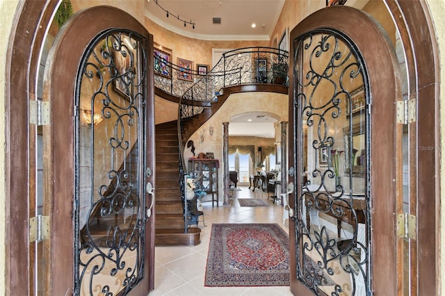 entryway with a high ceiling, crown molding, and light tile patterned flooring