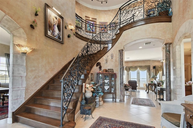 foyer entrance with ornamental molding, a high ceiling, and decorative columns