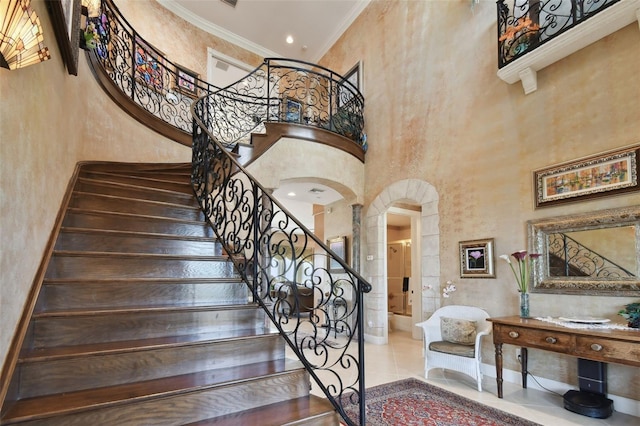 staircase with ornamental molding and a high ceiling