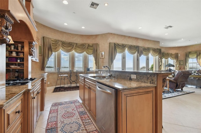 kitchen featuring dark stone countertops, sink, appliances with stainless steel finishes, a water view, and light tile patterned floors