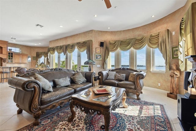 living room with ceiling fan, light tile patterned floors, and a water view