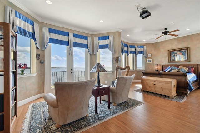 sitting room featuring hardwood / wood-style flooring, ceiling fan, french doors, ornamental molding, and a water view