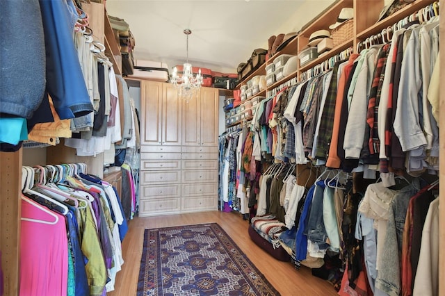 spacious closet with light wood-type flooring and an inviting chandelier