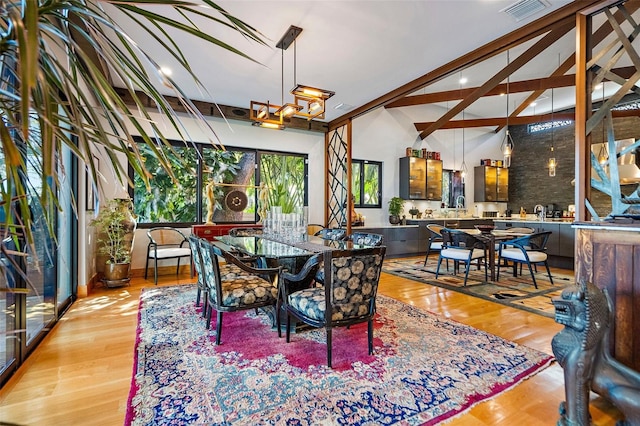 dining space with high vaulted ceiling and light hardwood / wood-style floors