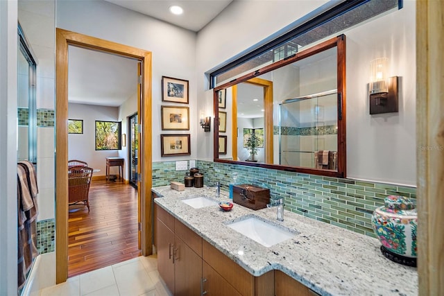 bathroom with an enclosed shower, vanity, decorative backsplash, and tile patterned floors