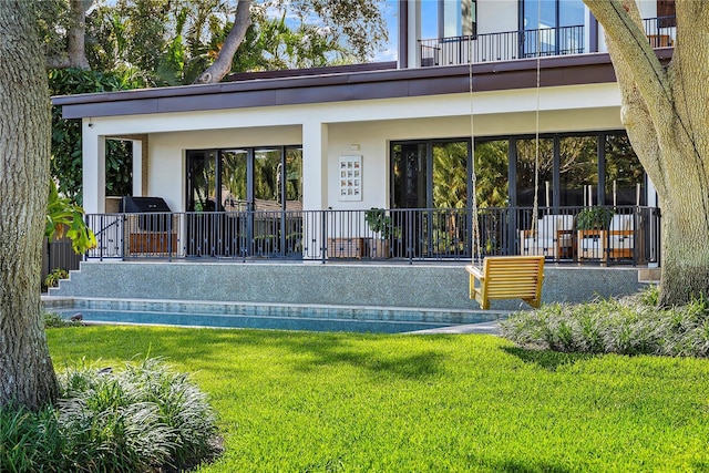 rear view of property featuring a lawn and a balcony