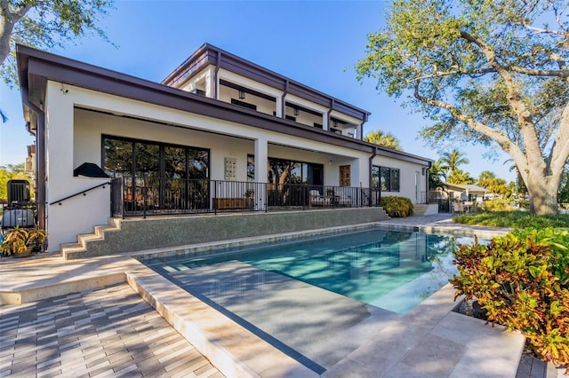 back of property with a fenced in pool and a patio area