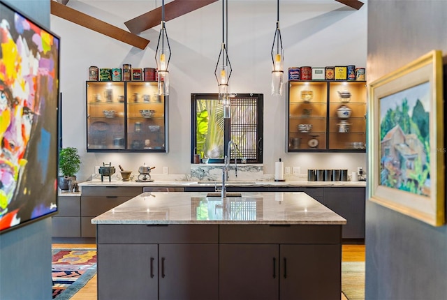 bar featuring decorative light fixtures, sink, beamed ceiling, light hardwood / wood-style flooring, and light stone countertops