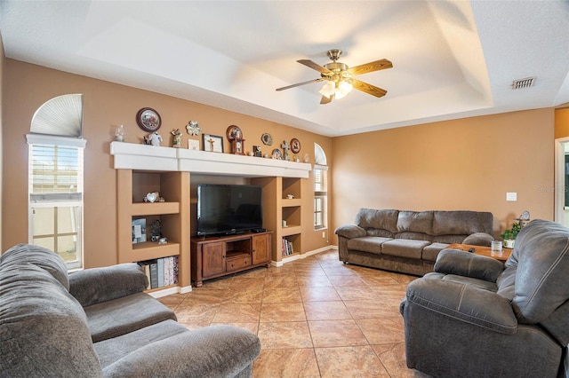 tiled living room featuring a tray ceiling and ceiling fan