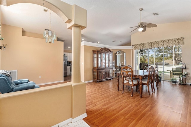 dining room featuring ceiling fan with notable chandelier, lofted ceiling, hardwood / wood-style floors, and decorative columns