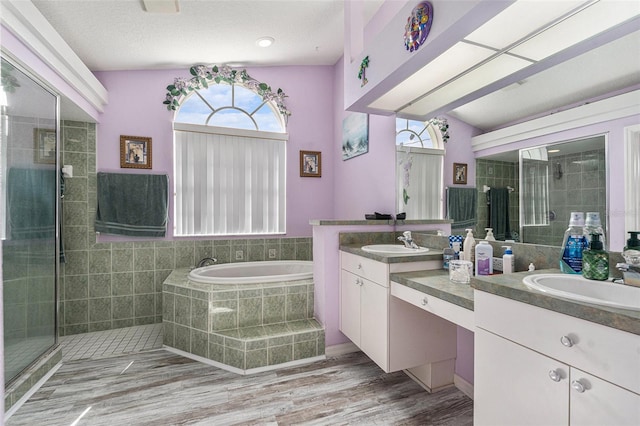 bathroom with independent shower and bath, vanity, hardwood / wood-style floors, and a textured ceiling