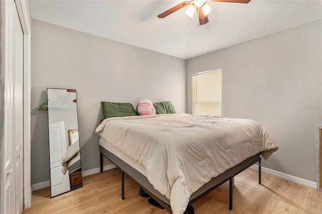 bedroom with ceiling fan, light hardwood / wood-style flooring, and a textured ceiling