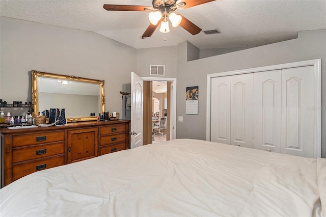 bedroom with lofted ceiling, a textured ceiling, a closet, and ceiling fan