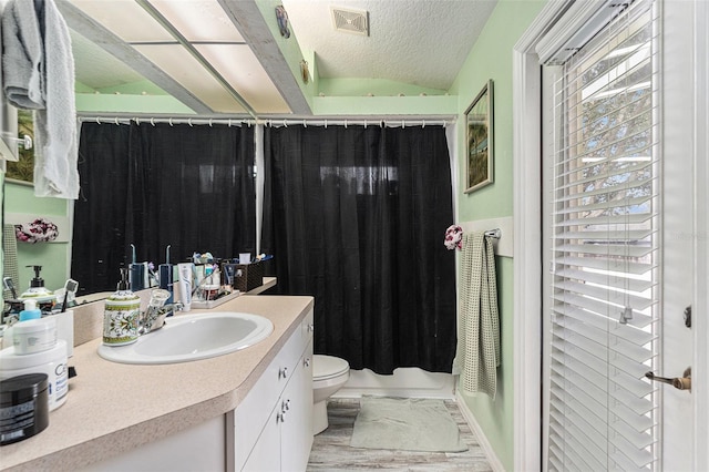 full bathroom with hardwood / wood-style floors, vanity, toilet, shower / bathtub combination with curtain, and a textured ceiling