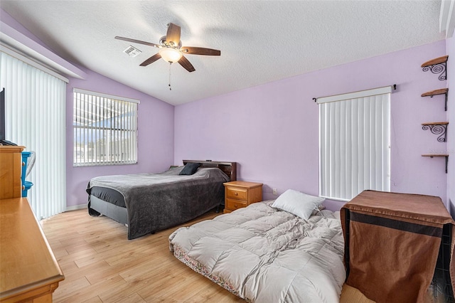 bedroom with ceiling fan, lofted ceiling, a textured ceiling, and light wood-type flooring