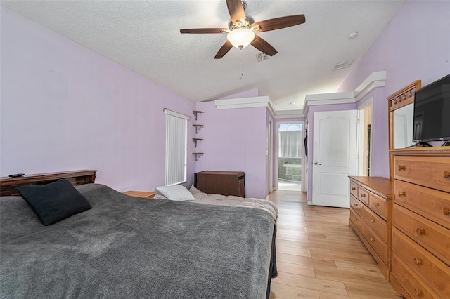 bedroom featuring ceiling fan, vaulted ceiling, light hardwood / wood-style flooring, and a textured ceiling